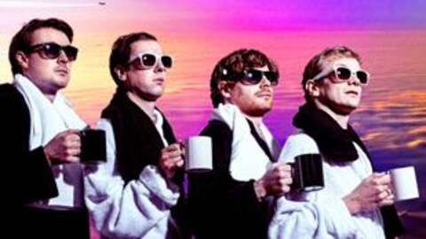 Les membres du groupe Django Django boivent un café devant un coucher de soleil.