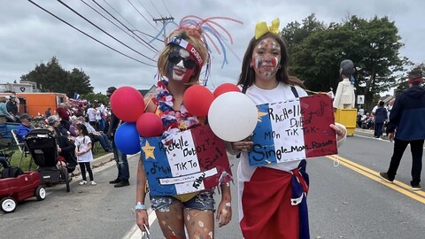 Deux jeunes filles costumées aux couleurs de l’Acadie dans la rue. 