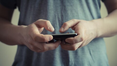 Doigts appuyant sur l'écran d'un téléphone cellulaire.