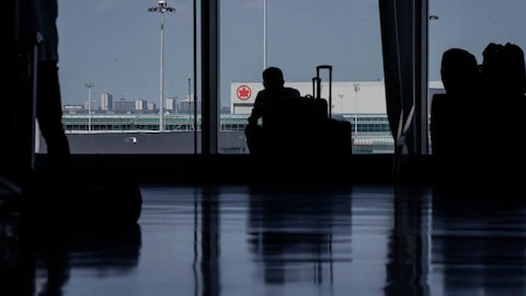 Travellers waiting around in departures at an airport.