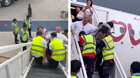 Des employés transporte une personne handicapée en bas d'un escalier d'un avion.
