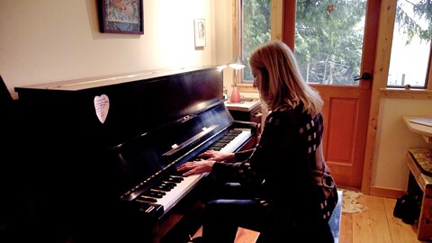 La musicienne Anna Lumière joue du piano dans sa petite maison sous les arbres.