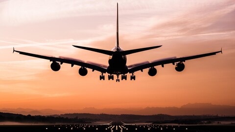 Un avion en train d'atterrir au coucher du soleil.