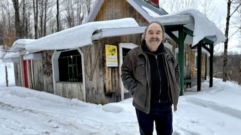 Réjean Bilodeau devant un petit bâtiment en bois.