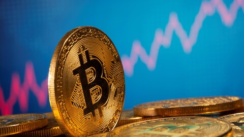 Une pièce illustrant un bitcoin devant un graphique boursier. 