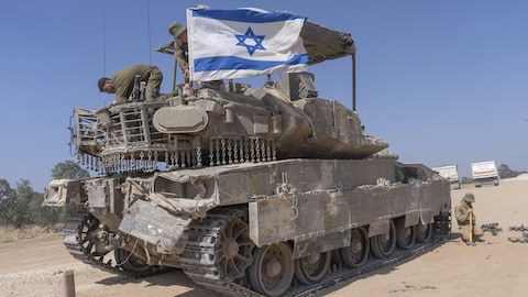 Un soldat israélien attache un drapeau à un blindé.