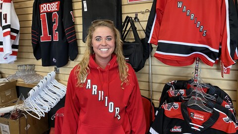 Cassidy Maier dans un magasin de Moose Jaw, en Saskatchewan, devant des chandails à l'effigie de l'équipe de hockey junior des Warriors, le 29 mai 2024.