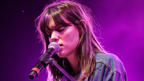 La chanteuse Charlotte Cardin chante les yeux fermés avec un micro très près de sa bouche.