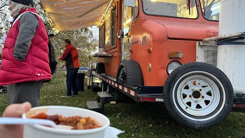 Un participant tient du chili, devant un food-truck.