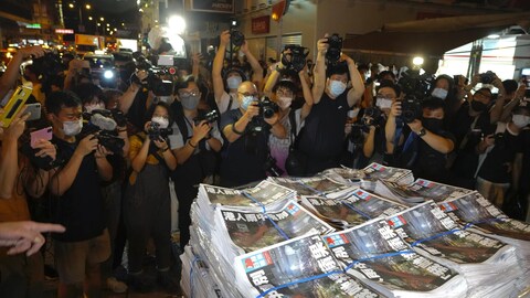 Des journalistes prennent en photo des piles de journaux.