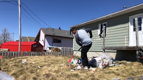 Un homme râtelle des déchets sur un terrain.