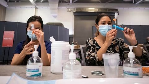 Workers prepare doses at a COVID-19 vaccination clinic in Vancouver. New guidelines suggest certain high-risk groups could benefit from having another dose of COVID-19 vaccines this spring. 