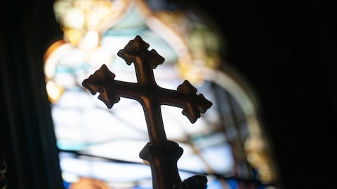 Photo d'une croix avec un vitrail en arrière-fond.