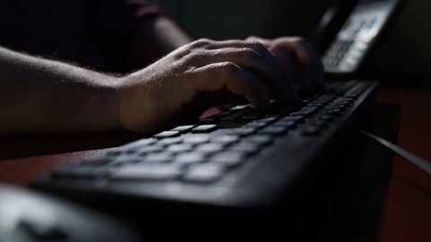 Un homme tape sur un clavier d'ordinateur.