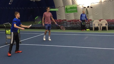 Un jeune et un adulte qui jouent au tennis