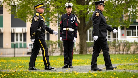 Trois policiers en uniforme qui défilent. 
