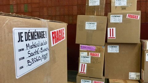 Des boîtes de déménagement empilées dans un local de le bâtiment administratif du campus d’Alfred.