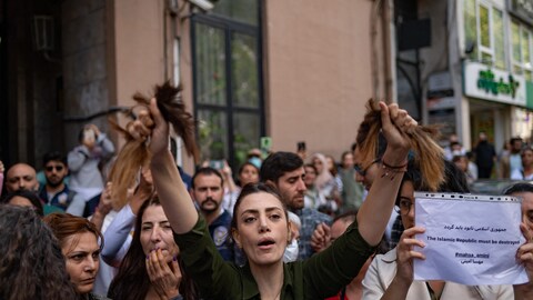 Une Iranienne vivant en Turquie, brandit ses cheveux après les avoir coupés avec une paire de ciseaux. 