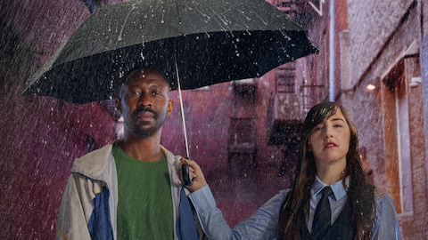 Sous la pluie, Florence Longpré tient un parapluie au-dessus de Thomas Ngijol.