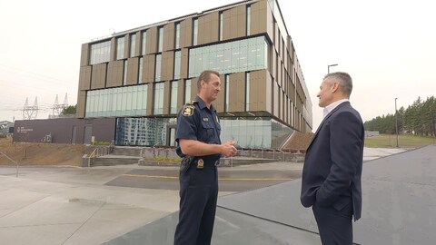 Deux hommes discutent devant la nouvelle centrale de police de Québec. 