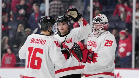 Joshua Roy célèbre la victoire du Canada face à l'Autriche avec ses coéquipiers Connor Bedard et Benjamin Gaudreau.