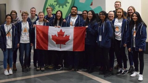Une douzaine d'étudiants devant un drapeau canadien. Une douzaine d'étudiants devant un drapeau canadien.