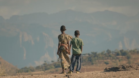 Deux enfants regardent les montagnes au loin.