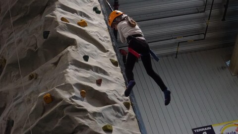 Une fillette fait de l'escalade à l'intérieur.