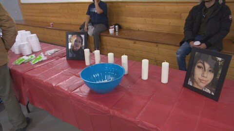 Les photos de Morgan Beatrice Harris et de Marcedes Myran sont disposées sur une table recouverte d'une nappe rouge, sur laquelle se trouvent des bougies. 