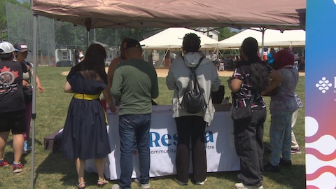Des personnes debout devant un kiosque le 14 juin 2025 à Winnipeg.