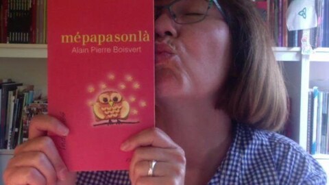 Une femme embrasse un livre rouge intitulé « Mépapasonlà », de l'écrivain Alain Pierre Boisvert.