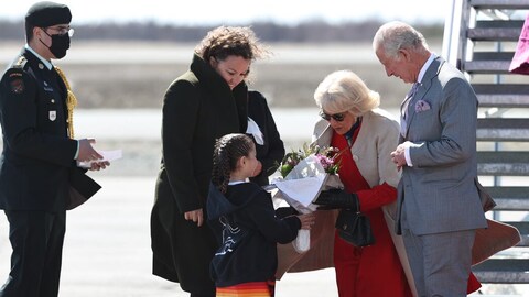 Le prince Charles et la duchesse de Cornouailles reçoivent un bouquet de fleurs au pied d'un escalier sur le tarmac de l'aéroport de Yellowknife, le jeudi 19 mai 2022.