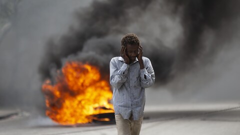 Un homme marche devant une colonne de feu dans une rue.