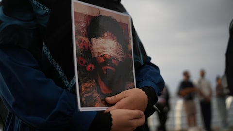 Une femme tient un dessin qui représente un homme aux yeux bandés.