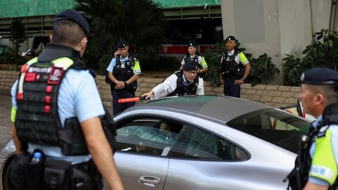 Police officers outside a building speak to someone in their car.