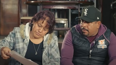 Une femme lit un document, un homme à ses côtés regarde le même document. 