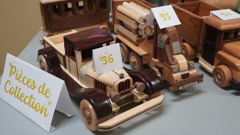 Des camions en bois sont exposés sur une table. 