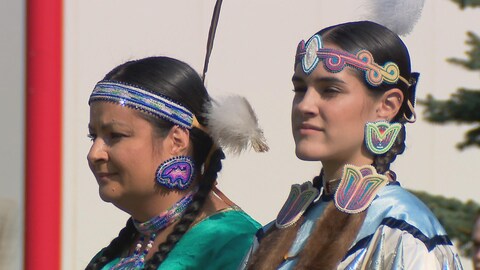 Deux femmes portent une tenue traditionnelle autochtone. Elles regardent au loin.