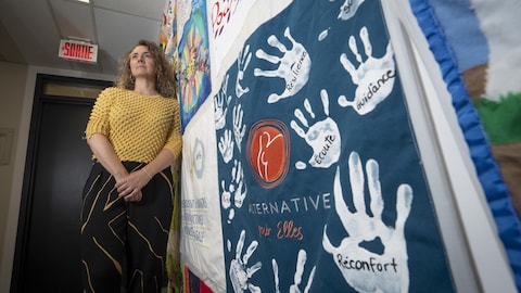 Karine Barrette devant une murale qui porte des messages de solidarité et de réconfort.