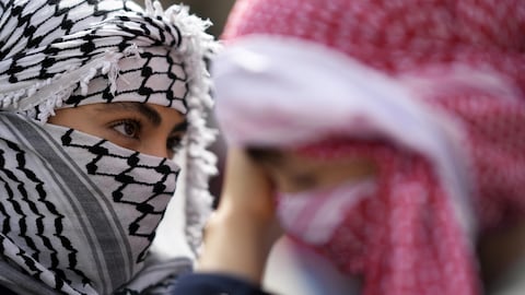 امرأة ترتدي كوفية وتساعد طفلاً على تعديل كوفيته خلال تظاهرة دعم للفلسطينيين في العاصمة البرتغالية لشبونة في 7 نيسان (أبريل) الجاري طالب فيها المشاركون بوقف إطلاق النار في قطاع غزة.