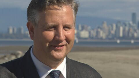 Kennedy Stewart et la ville de Vancouver en arrière-plan, il est sur une plage Kennedy Stewart et la ville de Vancouver en arrière-plan, il est sur une plage