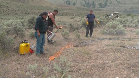Joe Gilchrist, avec deux personnes de la communauté, pratique un brûlage contrôlé.