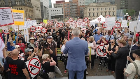 Radio-Canada Une foule de manifestants avec des pancartes contre le TGV écoutent un discours.