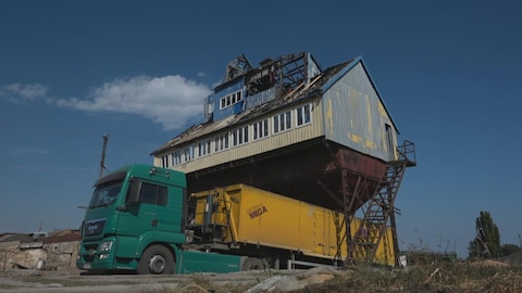Camion de récoltes en Ukraine au dessous d'un bâtiment agricole détruit par la guerre.