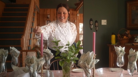 Une femme allume une bougie sur une table.
