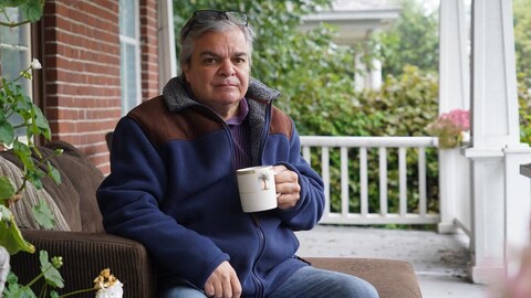 Louis Kavaratzis assis sur sa galerie devant sa maison.