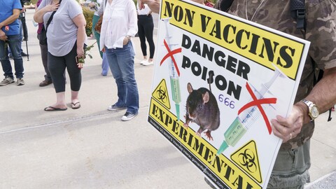 Gros plan sur une pancarte que brandit un manifestant lors d'un rassemblement antivaccins devant un hôpital montréalais. On peut lire Non Vaccins, Danger poison, 666, Expérimental.