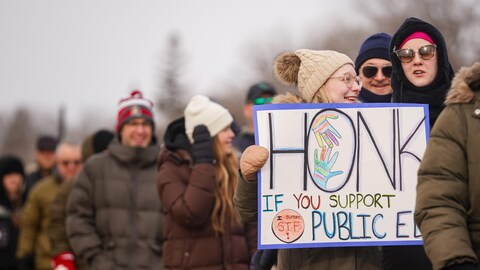 Un groupe de personnes manifeste avec des membres de la Fédération des enseignants de la Saskatchewan (STF) devant le Palais législatif de la Saskatchewan, le 20 mars 2024.