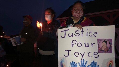 Une femme tient une affiche où il est inscrit « Justice pour Joyce ».