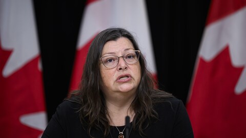 Une femme donne une allocution devant des drapeaux du Canada durant une conférence de presse, à Ottawa, le 27 novembre 2023.